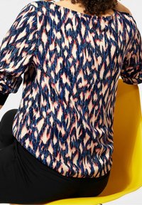 Blusa con motivo a disegno astratto nei colori blu navy, rosso e crema; presenta maniche arricciate e scollo off-shoulder.