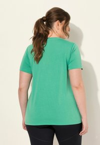 Triko s krátkým rukávem a kulatým výstřihem v živé zelené barvě. Měkká textura a volný střih, s jednoduchým designem a mírnou pružností.