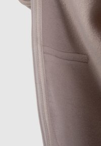 Grå stof med en glat tekstur, der har en lynlåslukning og en indvendig lomme. Designet er enkelt og funktionelt.