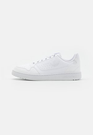 Hvid lavtop Adidas sneaker med perforerede detaljer og præget logo på siden, flad sål og snørelukning.