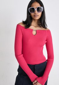 Top lungo aderente rosa a costine con design off-shoulder e dettaglio a chiave sul collo. Tessuto testurizzato con una finitura liscia.