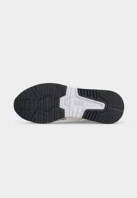 Σόλα αθλητικού παπουτσιού με μοτίβα από μαύρο και λευκό καουτσούκ, με το λογότυπο «asics» ανάγλυφο στη μέση.