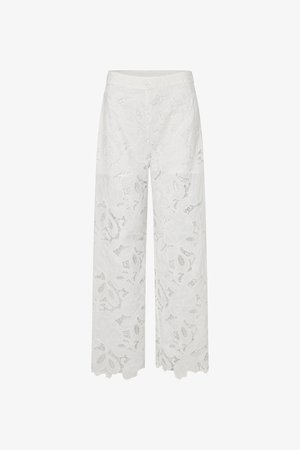 Białe spodnie o szerokich nogawkach z kwiatowym wzorem koronki i falowanym dołem, wykonane z prześwitującego materiału, z wysokim stanem.