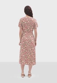 Abito con stampa floreale caratterizzato da maniche corte, vita aderente e gonna svasata. Il materiale è leggero con uno sfondo beige e motivi rossi.