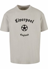Lichtgrijs katoen T-shirt met zwarte tekst "Liverpool" en "Engeland" met een zwart voetbalsymbool gecentreerd tussen de woorden.