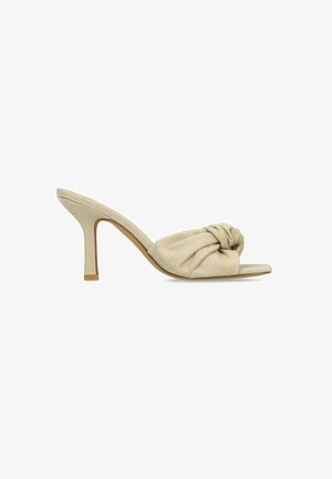 Mule à talon haut beige avec bout ouvert et détail en tissu torsadé sur le devant, vue de profil sur fond blanc.