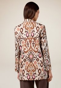 Blazer con trama che presenta disegni intricati in tonalità di marrone, rosa e blu, con una superficie texturizzata e una vestibilità sartoriale.