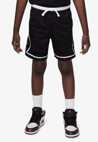 Black athletic shorts with white trim and drawstring, paired with high-top sneakers featuring a mix of black, white, and copper accents.