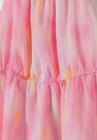 Růžová šifonová tkanina s hladkým povrchem, která má na sobě nařasený pas a diskrétní oranžové a žluté akcenty, čímž vytváří jemný přechodový efekt.
