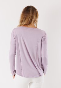 Maglia a manica lunga di un leggero colore viola, con una vestibilità ampia, dotata di un collo rotondo e dettagli a taglio vivo all'orlo. Tessuto morbido ed elastico.