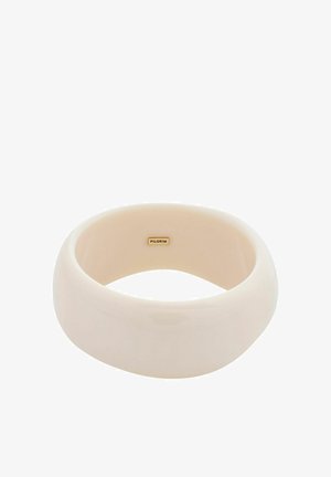 Glanzende beige armband van gladde hars. Ronde vorm met een gelijkmatige oppervlakte en een klein gouden logo aan de binnenkant.