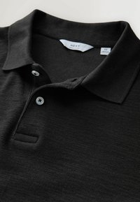 Fekete közepes méretű galléros póló két fehér gombbal és hajtókás gallérral, "Next Regular Fit" felirattal.