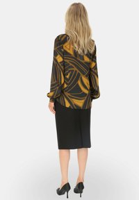 Czarna spódnica zestawiona z długim rękawem topem w żółto-czarny abstrakcyjny wzór, wykonanym z teksturowanej tkaniny, z luźnymi rękawami.