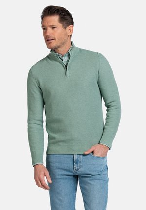 Groene gebreide trui met een kwart rits kraag, slim fit en textuurstof, gecombineerd met lichtblauwe jeans.