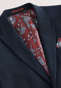 Marineblazer mit glatter Textur; verfügt über ein blumenmuster-burgunderfarbiges Futter und ein Taschentuchfachdetail.