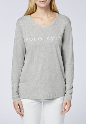 Graues Langarm-T-Shirt mit V-Ausschnitt und weißem "POLO SYLT"-Schriftzug über der Brust. Weiches Material; figurbetontes Design; kombiniert mit weißen Hosen.