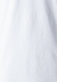 Fehér anyag, sima, egyenletes texture-el, enyhe gyűrődésekkel és dimenzionális eltérésekkel. Nincsenek látható minták vagy hardverek.