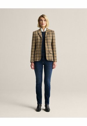 Brunternetternet blazer med en skræddersyet design, klapkraver og to knapper, parret med mørkeblå jeans og sorte ankelstøvler.