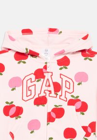 Rosa zip-up hoodie med stora tryck av röda och rosa äpplen, med en rymlig framficka och "GAP"-logotyp i röd brodering på bröstet.