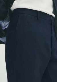 Marinblå, skräddarsydda byxor i ett mjukt tyg, med sidofickor och knäppning. Enkel design med figurnära passform.