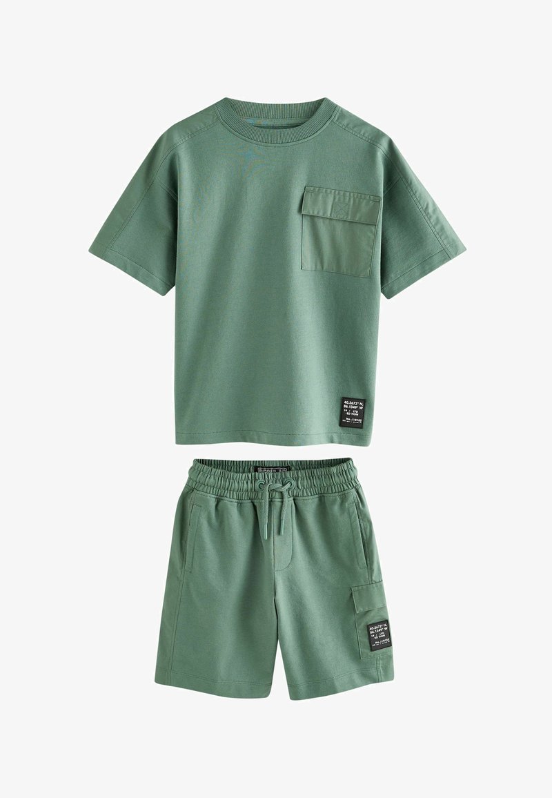 Chemise verte à manches courtes avec poche poitrine et short assorti à taille élastique avec cordon et poche latérale, tous deux avec des étiquettes noires.