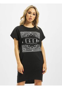 Czarna sukienka t-shirt z bawełny, z białym motywem paisley i grafiką "LEGEND" z przodu. Luźny fason z podwiniętymi rękawami i zaokrąglonym dołem.