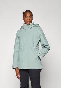 Lys teal vanntett jakke med hette, med glidelås, sidelommer og kontrasterende ermer. Enkelt design og myk tekstur.