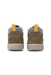Een paar bruine suède schoenen met grijze stofkragen en gele trekflappen, gezien vanaf de achterkant tegen een witte achtergrond.