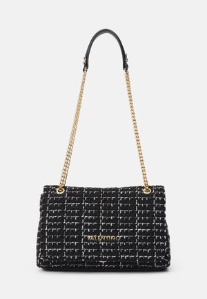 Czarno-biała torebka Valentino o fakturowanej powierzchni z złotym łańcuszkiem i czarnym skórzanym detalem na ramię na jednolitym tle.