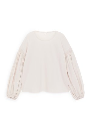 Top a maniche lunghe color beige chiaro con scollo rotondo e maniche voluminose con dettagli arricciati ai polsini. Tessuto morbido al tatto.