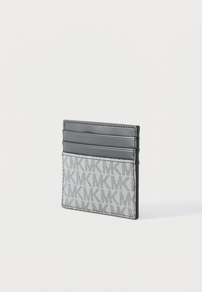 Porte-cartes gris et blanc en tissu texturé à motif, avec trois fentes pour cartes sur le dessus, placé debout sur une surface blanche.
