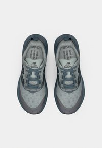 Chaussures de sport gris clair avec des accents bleu foncé. Tige en mesh pour la respirabilité, semelle rembourrée et semelle extérieure en caoutchouc nervurée pour l'adhérence.