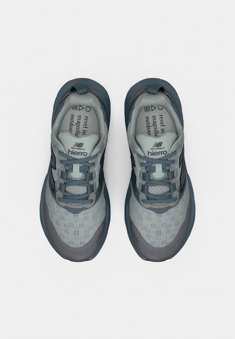Chaussures de sport gris clair avec des accents bleu foncé. Tige en mesh pour la respirabilité, semelle rembourrée et semelle extérieure en caoutchouc nervurée pour l'adhérence.