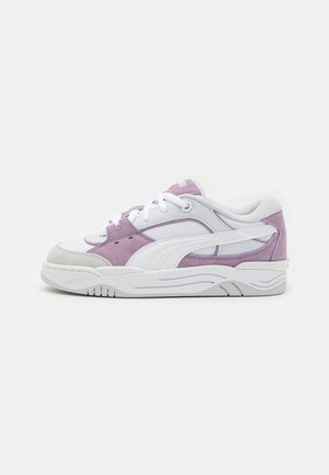 Des baskets Puma avec un design en cuir blanc et en suède lilas, bout rond, lacets blancs, et semelle en caoutchouc texturée avec des accents de vagues subtils.