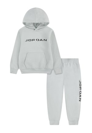 Tuta grigio chiaro composta da felpa con cappuccio e pantaloni, con logo nero "JORDAN" e silhouette Jumpman sul davanti e sulla gamba, vita elastica sui pantaloni.