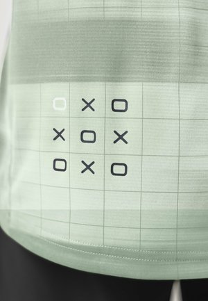 Tic-Tac-Toe-Gitter auf hellgrünem Stoff mit X- und O-Symbolen im abwechselnden Muster und einem weiß umrandeten Quadrat oben links.