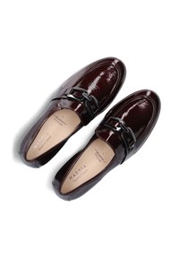 Donker bordeaux patent leren instappers met een decoratieve zwarte gesp, een gladde textuur, een ronde neus en een gevoerd voetbed met merklabel.
