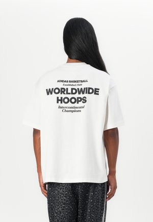 T-shirt blanc à manches courtes, avec un texte noir audacieux au dos : "ADIDAS BASKETBALL," "WORLDWIDE HOOPS," et "Champions Intercontinentaux."