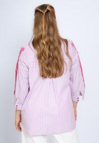 Gestreept shirt in roze en wit, met lange mouwen en decoratieve roze accenten, knoopdetails en een losse pasvorm.
