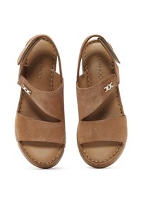 Brown suede sandals with cross straps and a buckle accent. Open toe design with a leather insole. Stitched sole detail visible.