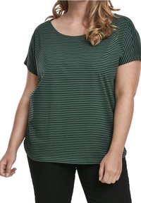 Zelený pruhovaný top s krátkým rukávem a kulatým výstřihem, s volným střihem a měkkou tkaninou. Nošený s černými kalhotami pro kontrast.