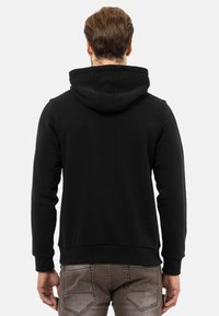 Schwarzer Kapuzenpullover aus Baumwollmischung. Verfügt über lange Ärmel sowie einen gerippten Saum und Bündchen. Schlichtes, elegantes Design.