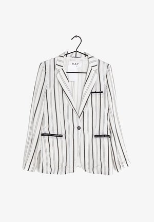 Blazer blanco con rayas verticales negras, cierre de un botón, solapas con muesca y dos bolsillos frontales con acentos de piping negro. Colgado de un gancho.