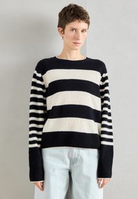 Sweater malha às riscas em azul marinho e creme. Apresenta riscas horizontais largas no corpo e riscas verticais estreitas nas mangas. Punhos canelados.