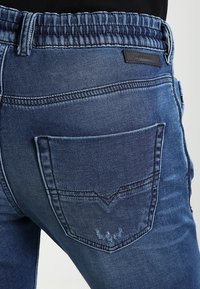 Vaqueros de denim con un lavado azul oscuro, que cuentan con una cinturilla acanalada, un bolsillo trasero con detalles de costura y una etiqueta de cuero con marca.