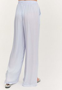 Svetlomodré široké nohavice z mäkkej tkaniny, s vertikálnymi bielymi pruhmi, elastickým pásom a bočnými vreckami.
