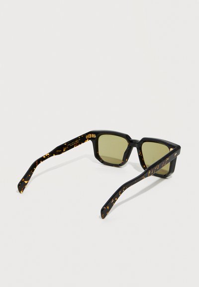 Black tortoiseshell rectangular sunglasses with green-tinted lenses, shown from a rear angled view on a white surface.