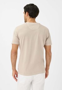 Beige kortærmet t-shirt med rund hals, der har en glat tekstur og synlige sømdetaljer. Bagsiden viser et enkelt design.