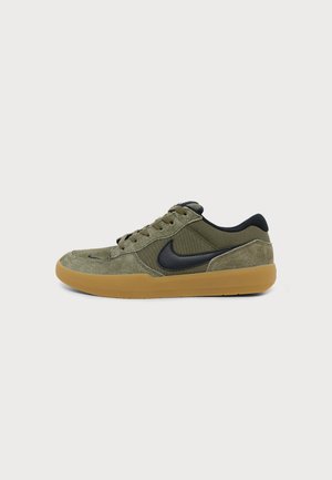Niedriger olivgrüner Sneaker mit schwarzem Nike-Swoosh und Gummisohle, von der Außenseite vor schlichtem Hintergrund gezeigt.
