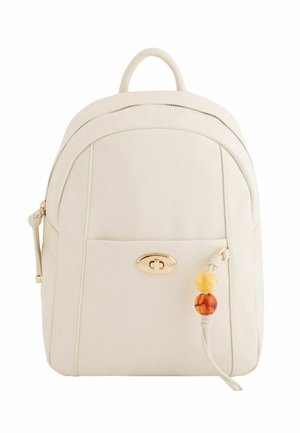 Mochila de cuero color crema con bolsillo frontal con cremallera, cierre giratorio dorado y cuentas decorativas amarillas y ámbar en el fleco de cuero.